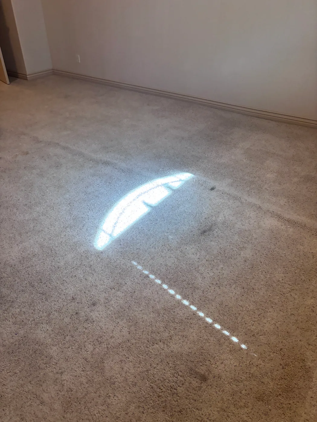 Flashlight beam showing a ridge in loose carpet before a 316 restretch